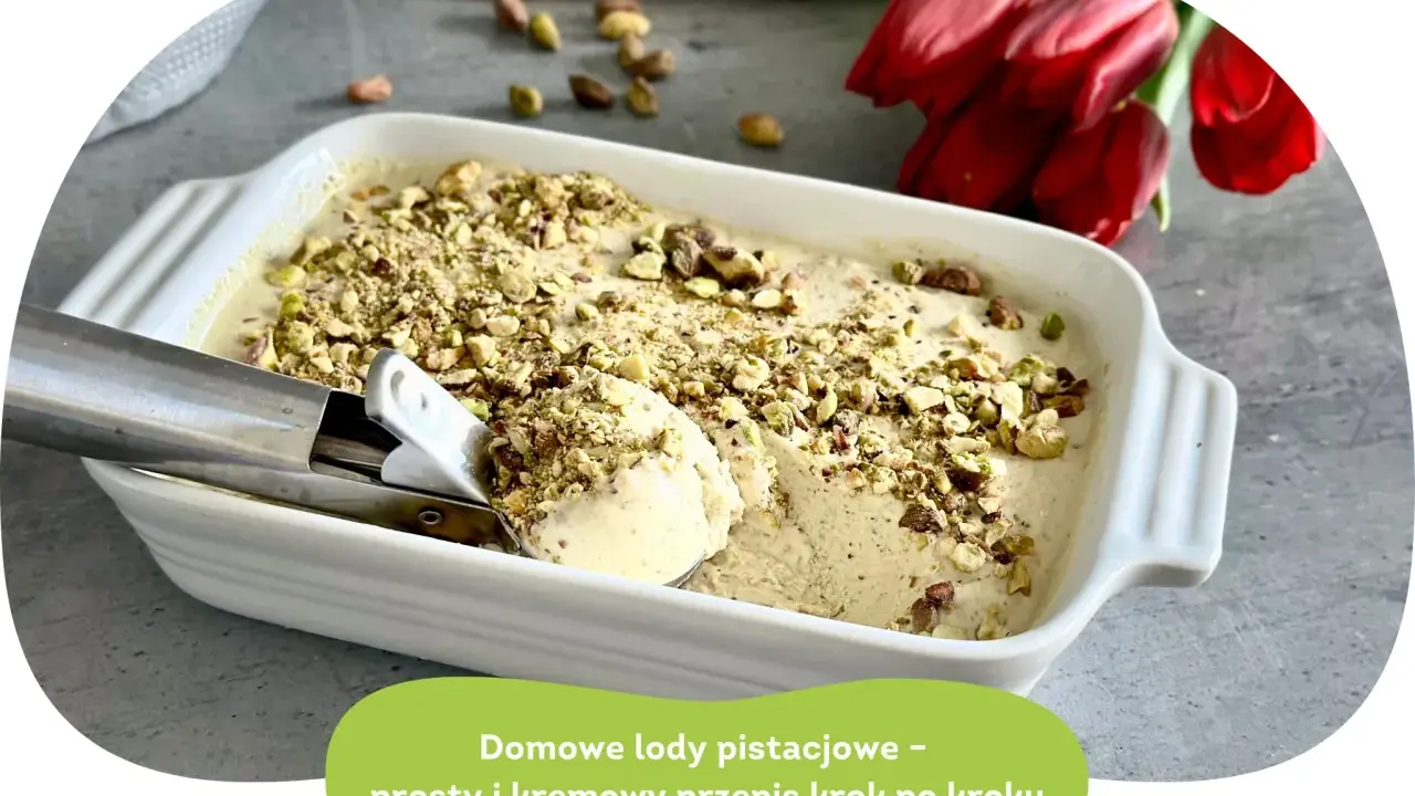 Kremowe lody pistacjowe w białej formie, posypane orzechami. Łyżka właśnie nabiera porcję tego pysznego deseru.
