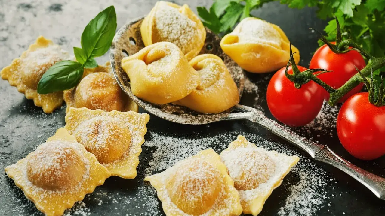 Świeże ravioli i tortellini, posypane cukrem pudrem, z pomidorkami koktajlowymi i bazylią. Idealne z czym podawać ravioli? Z prostym sosem!