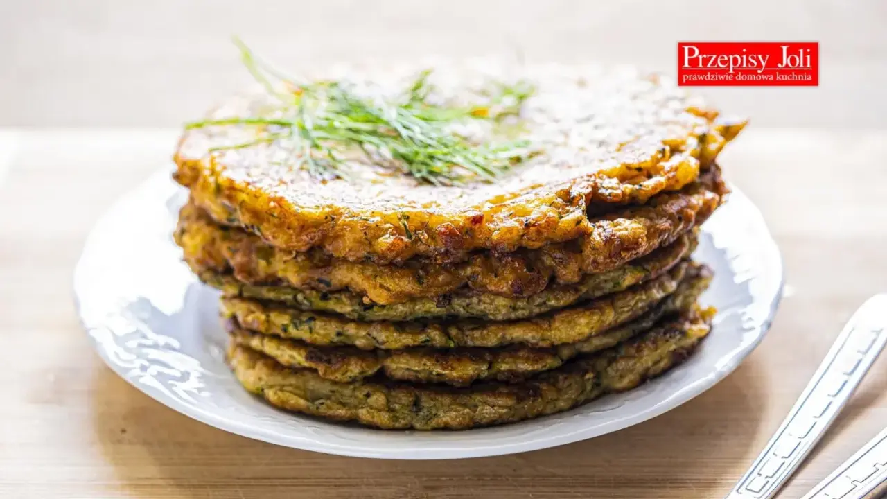 Stos placków z cukinii, idealnych jako dodatek do dania lub samodzielna przekąska. Ziołowy aromat i chrupiąca skórka zachęcają do spróbowania.