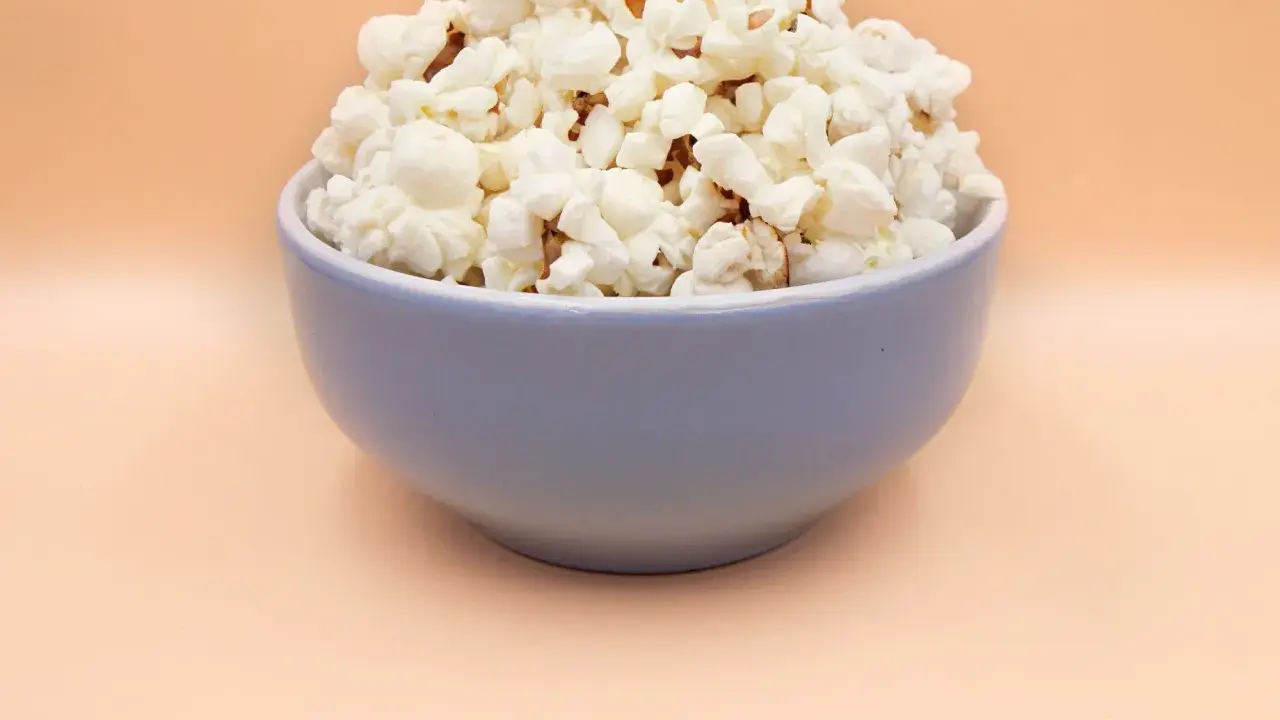 Pyszny, puszysty popcorn w niebieskiej misce. Idealny, gdy zastanawiasz się, jak zrobić popcorn na wieczór filmowy.