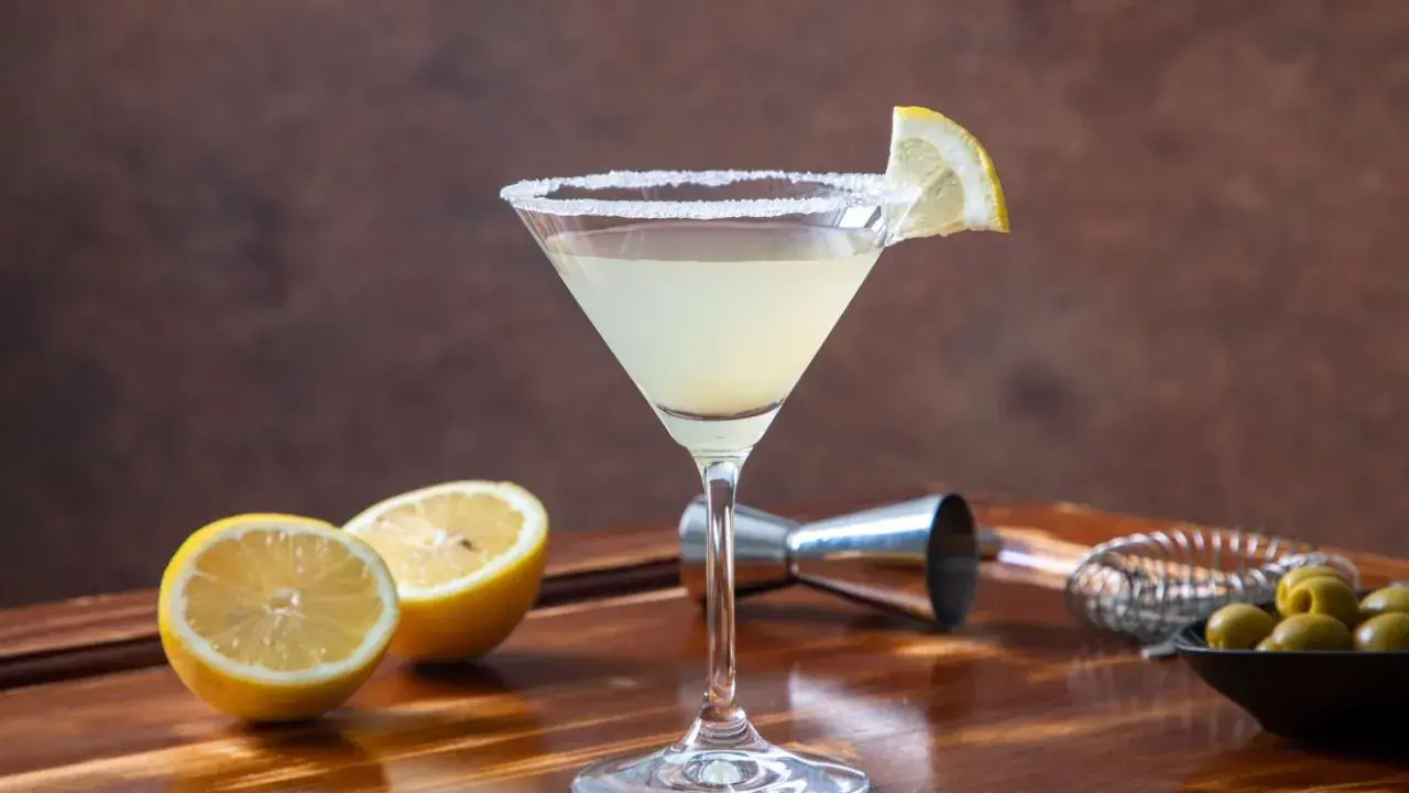 Orzeźwiające drinki z martini bianco, ozdobione cytryną i solą, obok świeżych cytryn i oliwek.