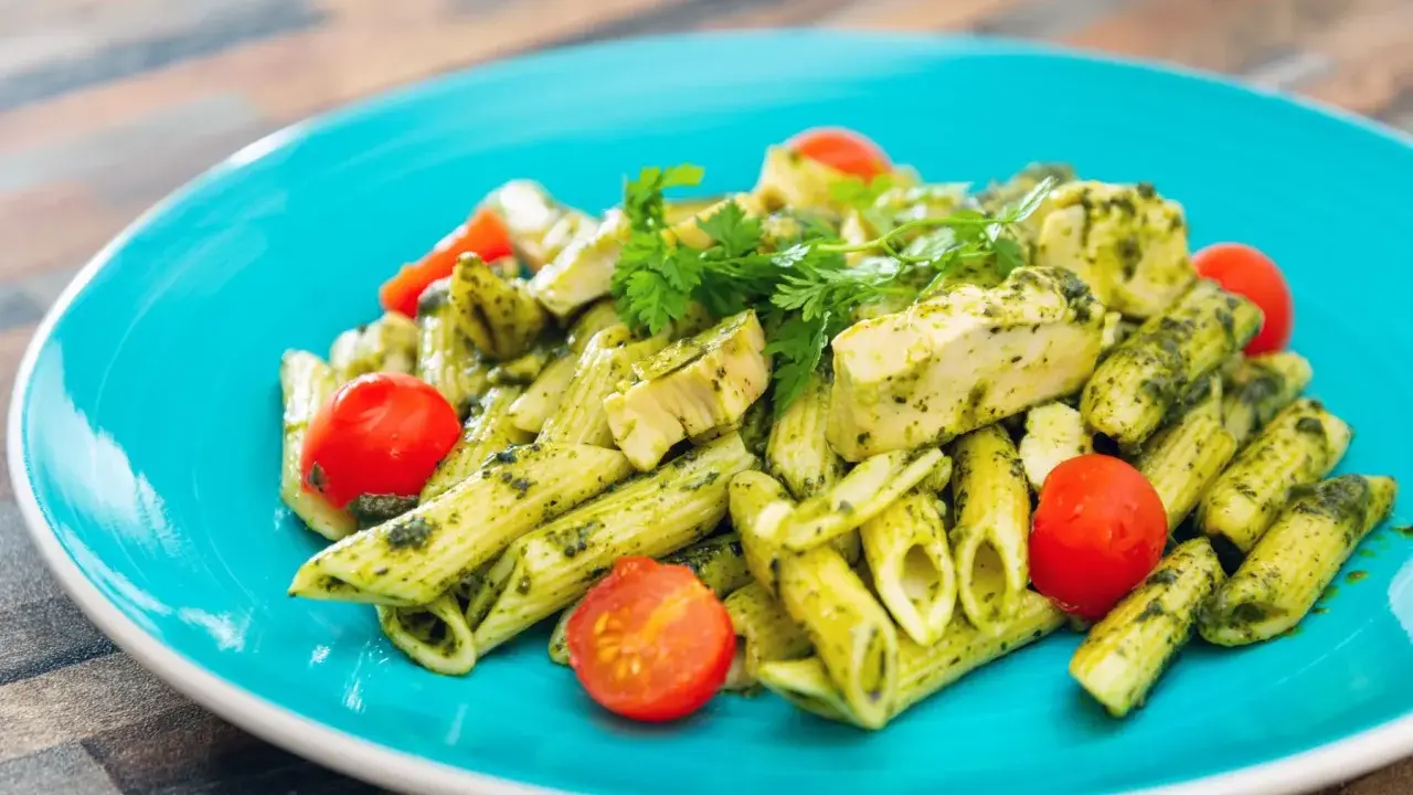 Penne z kurczakiem i pomidorkami koktajlowymi w sosie pesto, z dodatkiem mozzarelli.