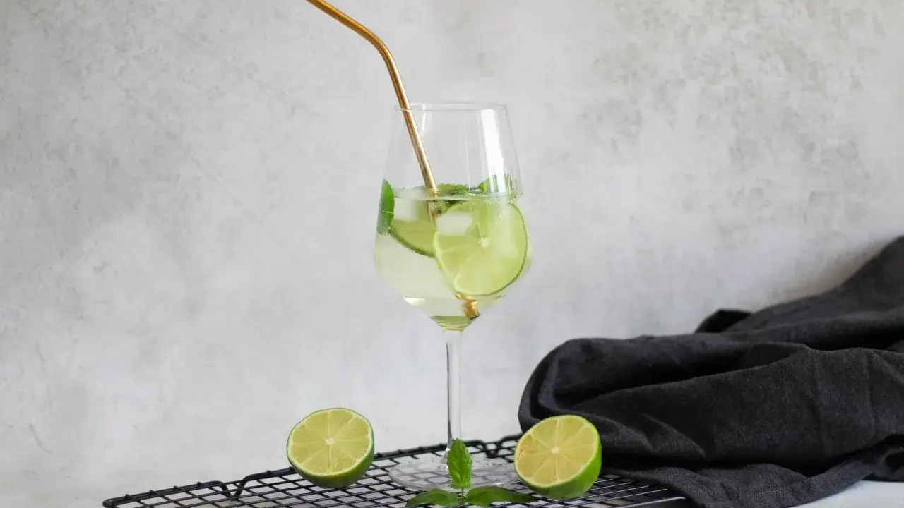 Orzeźwiający drink Hugo z limonką i miętą, idealne proporcje na lato. Złota słomka dodaje elegancji.