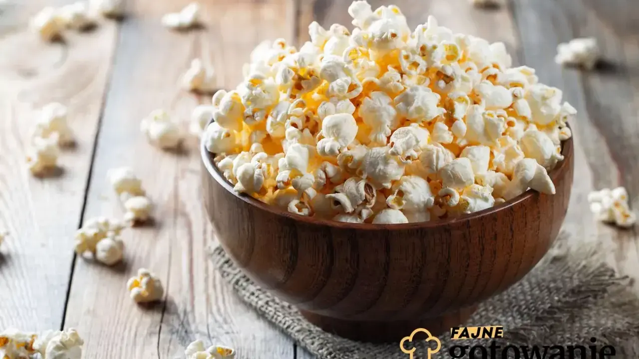 Pyszny popcorn w drewnianej misce, rozsypany na stole. Czy da się zrobić popcorn w piekarniku? Tak, i wygląda równie apetycznie!