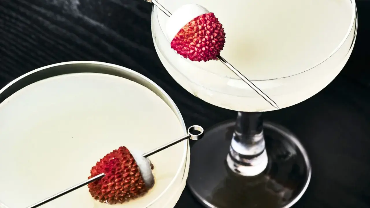 Dwa eleganckie drinki z liczi, ozdobione owocami na patyczkach, kuszą swoim orzeźwiającym wyglądem.