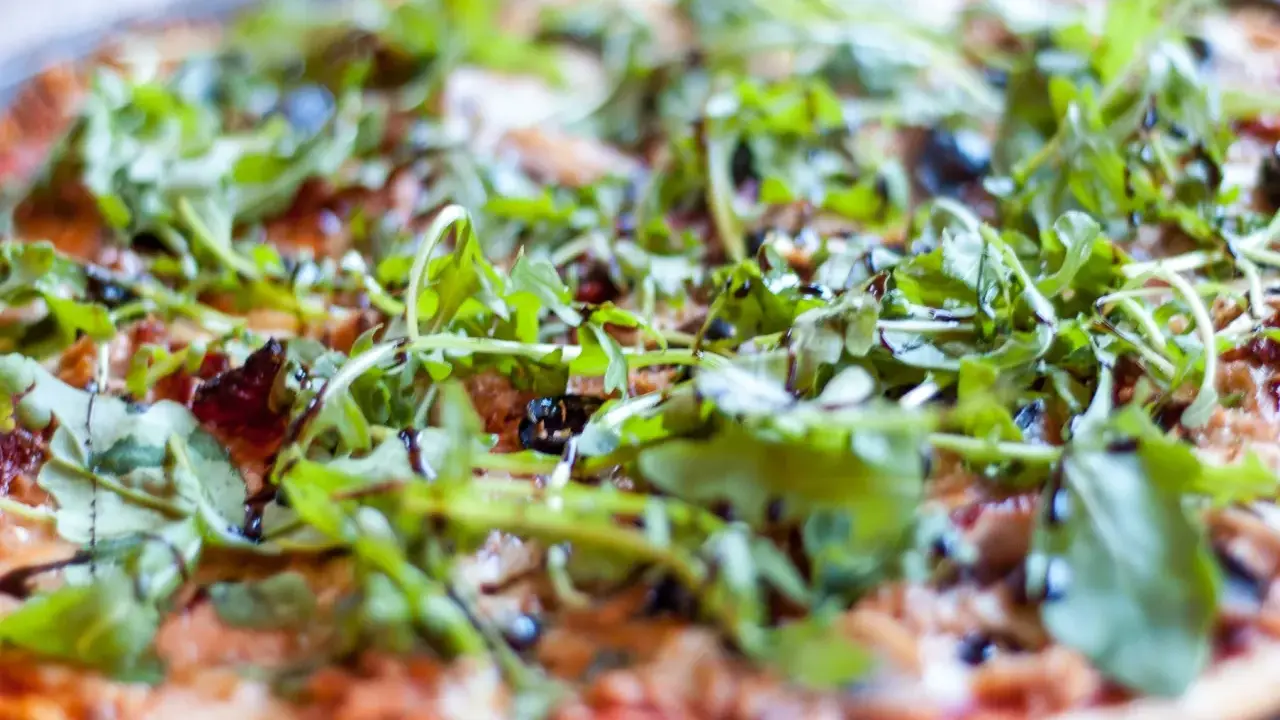Pyszna pizza z tuńczykiem, rukolą i oliwkami, polana sosem balsamicznym. Idealna na szybki obiad.