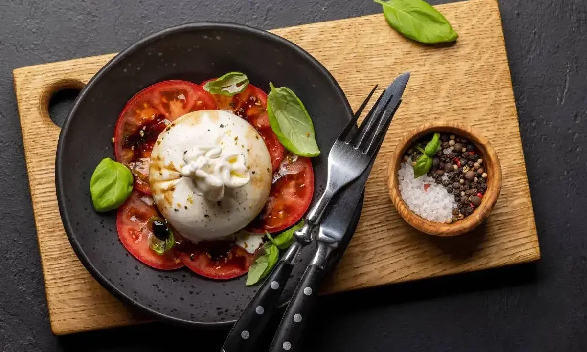 Ser burrata jak jeść? Pyszna sałatka z pomidorami, bazylią i kremowym serem. Idealna na lekki posiłek.