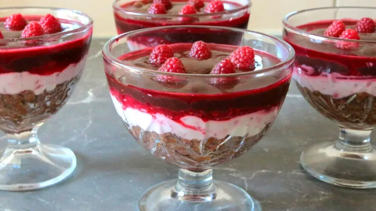 Mini deserki z mascarpone, przełożone warstwą musu i malinową galaretką, ozdobione świeżymi malinami.