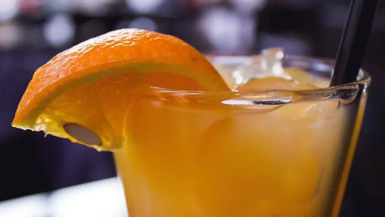 Orzeźwiający drink z suchym lodem, ozdobiony plasterkiem pomarańczy. Dymiący napój wygląda magicznie.