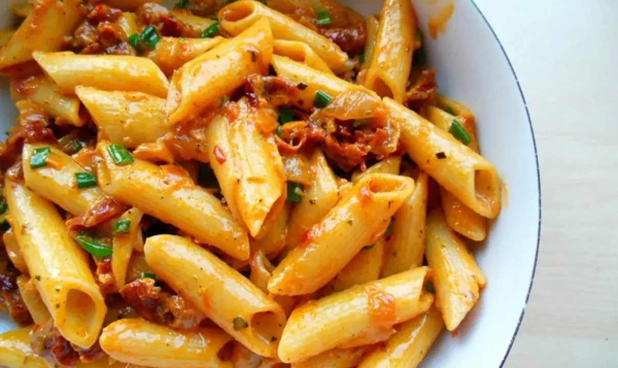 Penne z sosem z suszonych pomidorów i zieloną cebulką, apetyczne danie pełne smaku.
