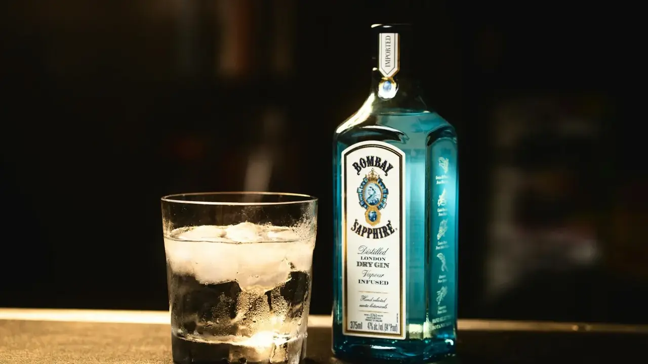 Szklanka z lodem i butelka Bombay Sapphire gin. Idealny składnik na orzeźwiający bombay sapphire drink.