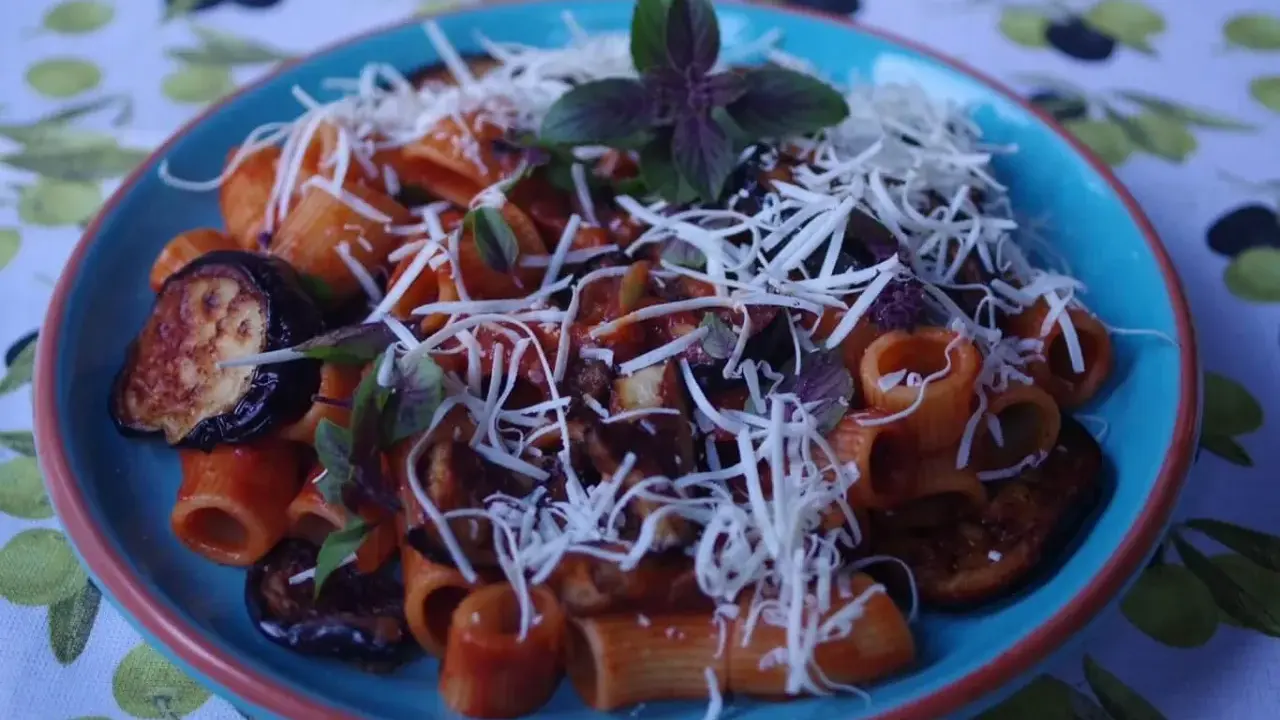 Rigatoni alla norma z bakłażanem, pomidorami i bazylią, posypane startym serem.