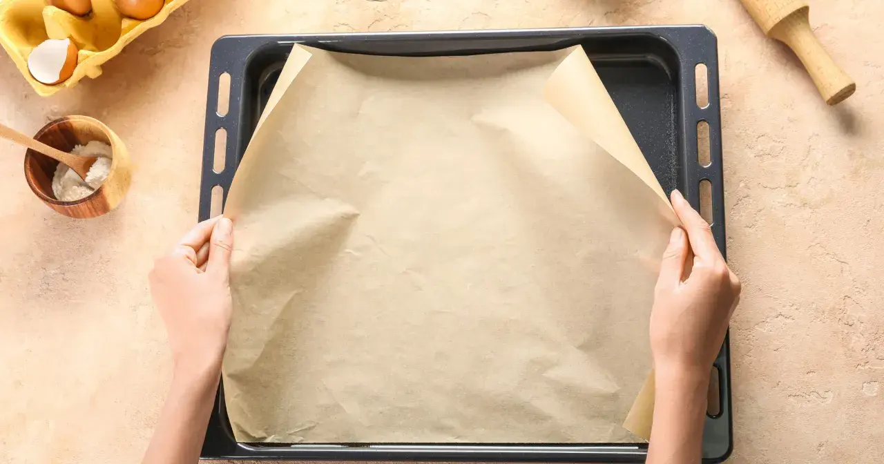 Ręce układają papier do pieczenia na blasze. To świetny sposób, by nic nie przywarło!