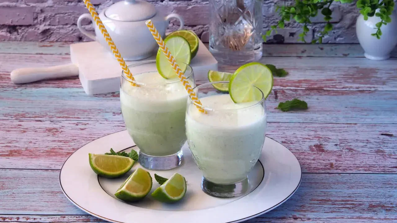 Dwa orzeźwiające drinki z mlekiem skondensowanym, ozdobione plasterkami limonki i miętą, na talerzu.