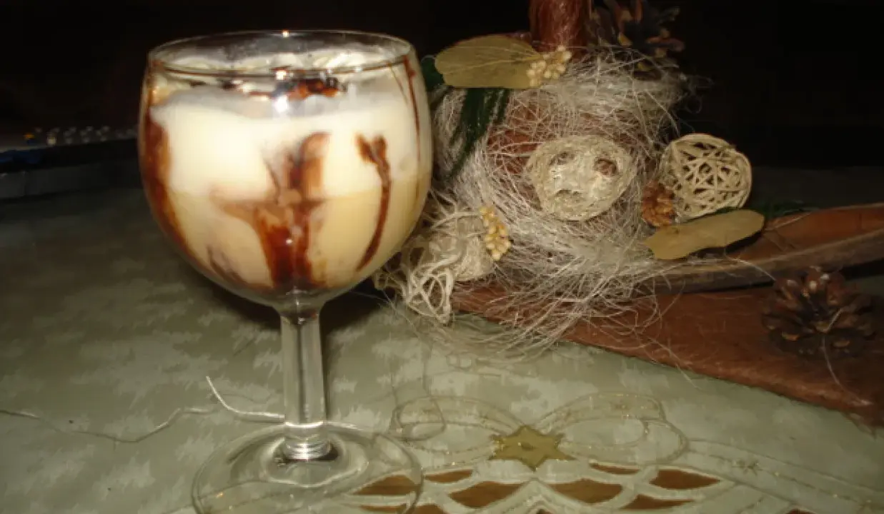 Pyszny drink z adwokatem, udekorowany czekoladą, na tle świątecznych ozdób.