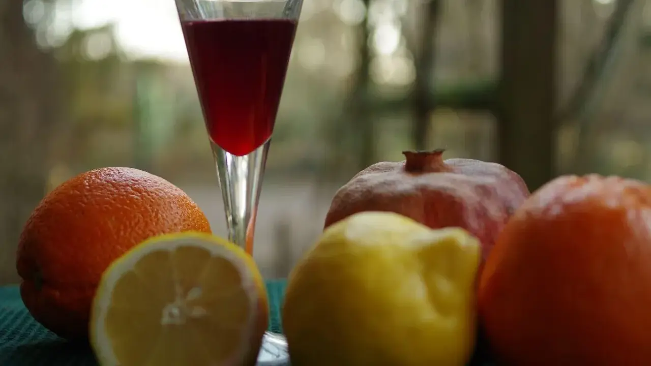 Szklanka z czerwonym napojem, obok pomarańcze, cytryna i granat. Czy to grenadyna? Hajduczek naturalnie.