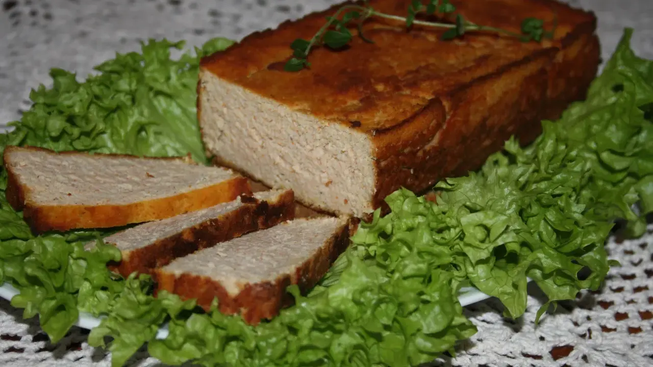 Pyszny pasztet drobiowy z wątróbką, pokrojony w plastry, podany na liściach sałaty. Idealny na kanapki.