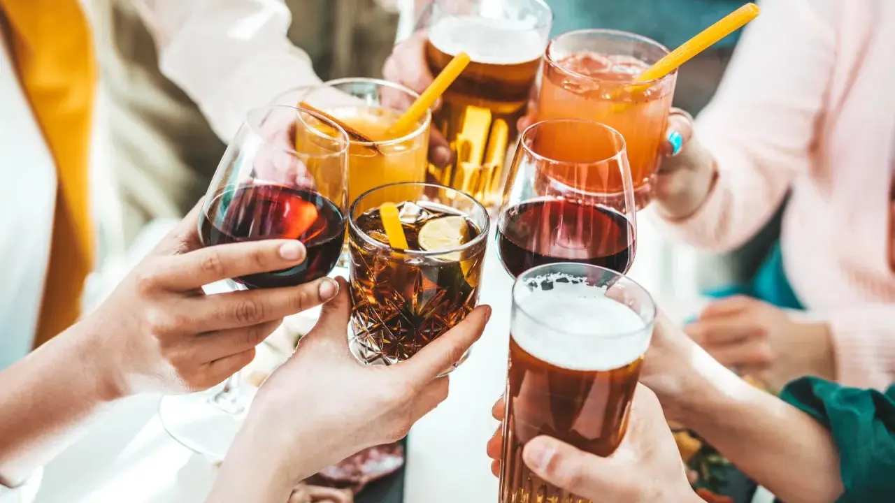 Ręce wznoszą kieliszki z winem, drinkami i piwem, celebrując wspólne chwile.