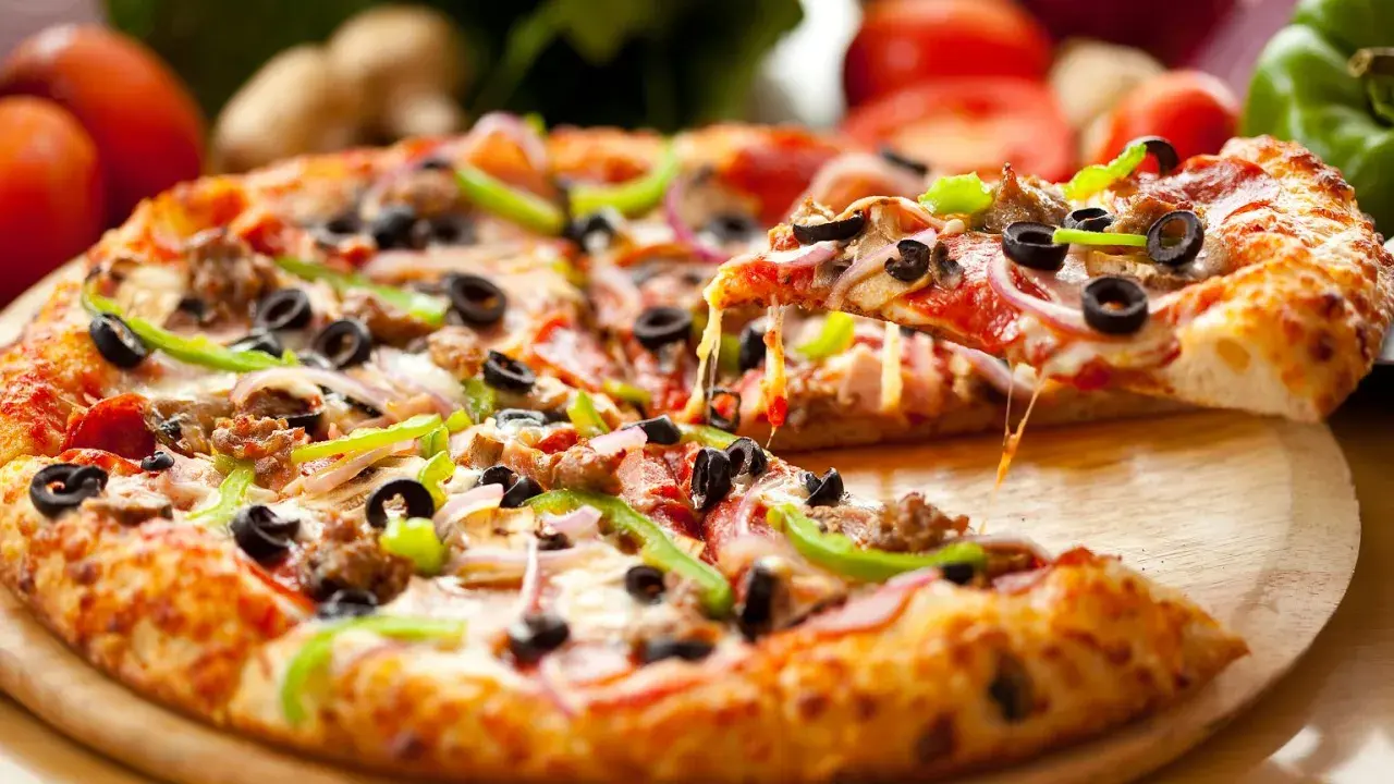 Gotowy spód do pizzy, z ciągnącym się serem, oliwkami, papryką i mięsem, aż chce się go włożyć do pieca!