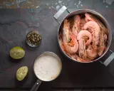Gotowane krewetki w garnku, obok sos, kapary i limonka. Idealne do prostego przepisu na krewetki.