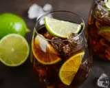 Orzeźwiający Cuba Libre z kostkami lodu i plasterkami limonki, gotowy do wypicia.