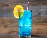 Orzeźwiający drink z blue curacao, ozdobiony plasterkiem pomarańczy i limonki, z kolorową słomką. Idealny na letnie popołudnie.