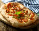 Pyszna focaccia z pomidorkami koktajlowymi i bazylią. Idealna jako przekąska lub dodatek do dania. Z czym jeść? Z sałatką, dipem lub solo!