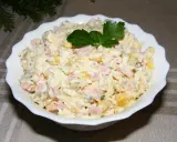 Pyszna sałatka z szynką, jajkiem, kukurydzą i ogórkiem, udekorowana natką pietruszki. Idealna na każdą okazję.