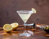 Orzeźwiające drinki z martini bianco, ozdobione cytryną i solą, obok świeżych cytryn i oliwek.