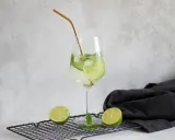 Orzeźwiający drink Hugo z limonką i miętą, idealne proporcje na lato. Złota słomka dodaje elegancji.