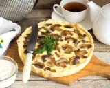Pyszna tarta z pieczarkami, podana z kubkiem herbaty i śmietaną. Idealna na jesienny obiad.