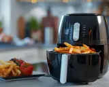 Frytki z frytkownicy beztłuszczowej, idealne do wypróbowania nowych air fryer przepisy. Obok talerz z frytkami, pomidorkami i oliwkami.