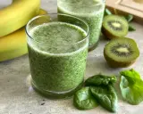 Orzeźwiający koktajl ze szpinakiem, bananami i kiwi. Zielony napój w szklance, obok świeże liście szpinaku i owoce.