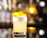 Klasyczny whisky sour z pianką i skórką cytryny, idealny na wieczór.