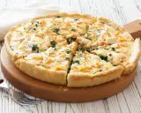 Pyszna tarta z łososiem, szpinakiem i serem feta, pokrojona na kawałki, czeka na talerzu.