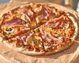 Pizza z szynką i pieczarkami do pizzy, pachnąca i apetyczna, gotowa do podania.