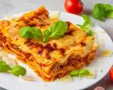 Pyszna, domowa lasagne jak z pieca, z warstwami makaronu, mięsa i sera, ozdobiona świeżą bazylią i parmezanem.