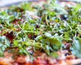 Pyszna pizza z tuńczykiem, rukolą i oliwkami, polana sosem balsamicznym. Idealna na szybki obiad.