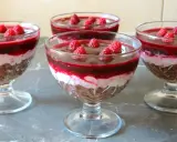 Mini deserki z mascarpone, przełożone warstwą musu i malinową galaretką, ozdobione świeżymi malinami.