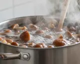 Gotujące się grzyby w garnku na kuchence. Woda wrze, a para unosi się w powietrzu. Zastanawiasz się, jak długo gotować grzyby?