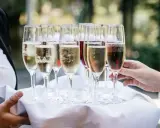 Taca z kieliszkami musującego wina, idealna do drinków typu Hugo. Zastanawiasz się, jakie prosecco do Hugo wybrać?