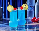 Dwa orzeźwiające drinki Blue Lagoon z cytryną i wiśnią, gotowe do podania.
