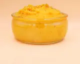 Pomarańczowe puree z batatów w szklanym naczyniu, posypane pieprzem.