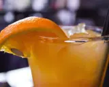Orzeźwiający drink z suchym lodem, ozdobiony plasterkiem pomarańczy. Dymiący napój wygląda magicznie.