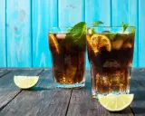 Dwa orzeźwiające drinki z rumem, lodem, miętą i limonką na drewnianym blacie.