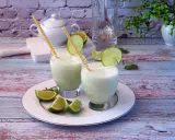 Dwa orzeźwiające drinki z mlekiem skondensowanym, ozdobione plasterkami limonki i miętą, na talerzu.