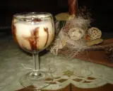 Pyszny drink z adwokatem, udekorowany czekoladą, na tle świątecznych ozdób.