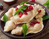 Pyszne, domowe ciasto na pierogi z wiśniami i miętą, podane na glinianym talerzu.