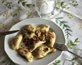 Pyszne pierogi ruskie z cebulką i boczkiem, gotowe do jedzenia. Obok widelec i nóż.