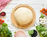 Świeże ciasto na pizzę, pomidorki, mozzarella, oliwki i szynka. Zastanawiasz się, ile może leżeć ciasto na pizzę w lodówce?